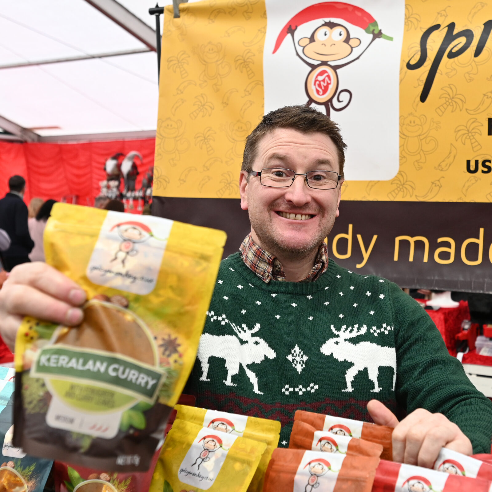 A smiling stallholder showing a curry sauce