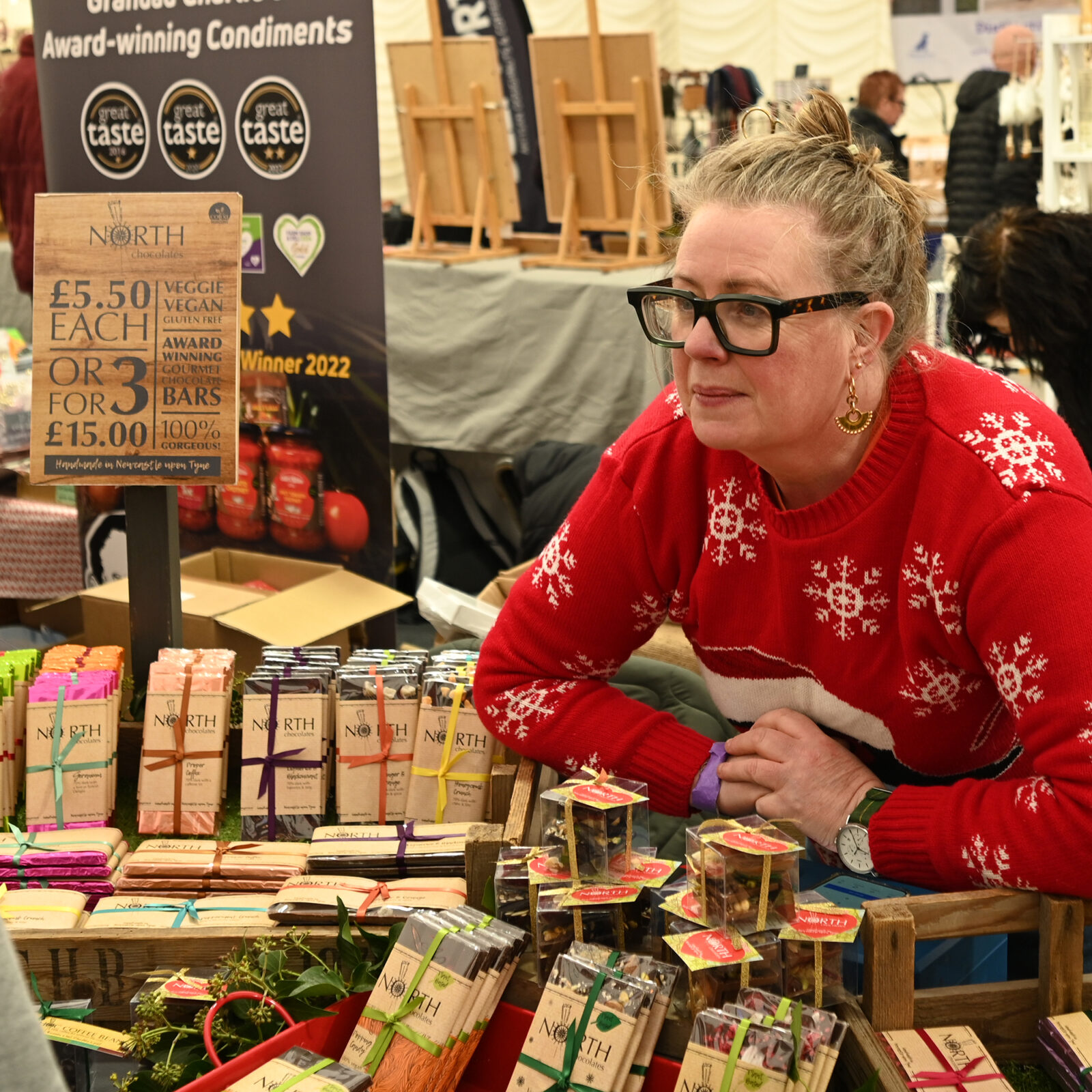 A stallholder leaning over a stall of chocolate bars