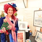 A lady in Victorian costume holding a rosette