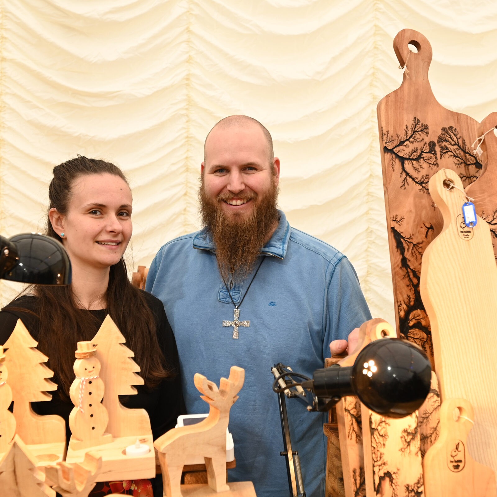 A couple selling wooden chopping boards and Christmas decorations