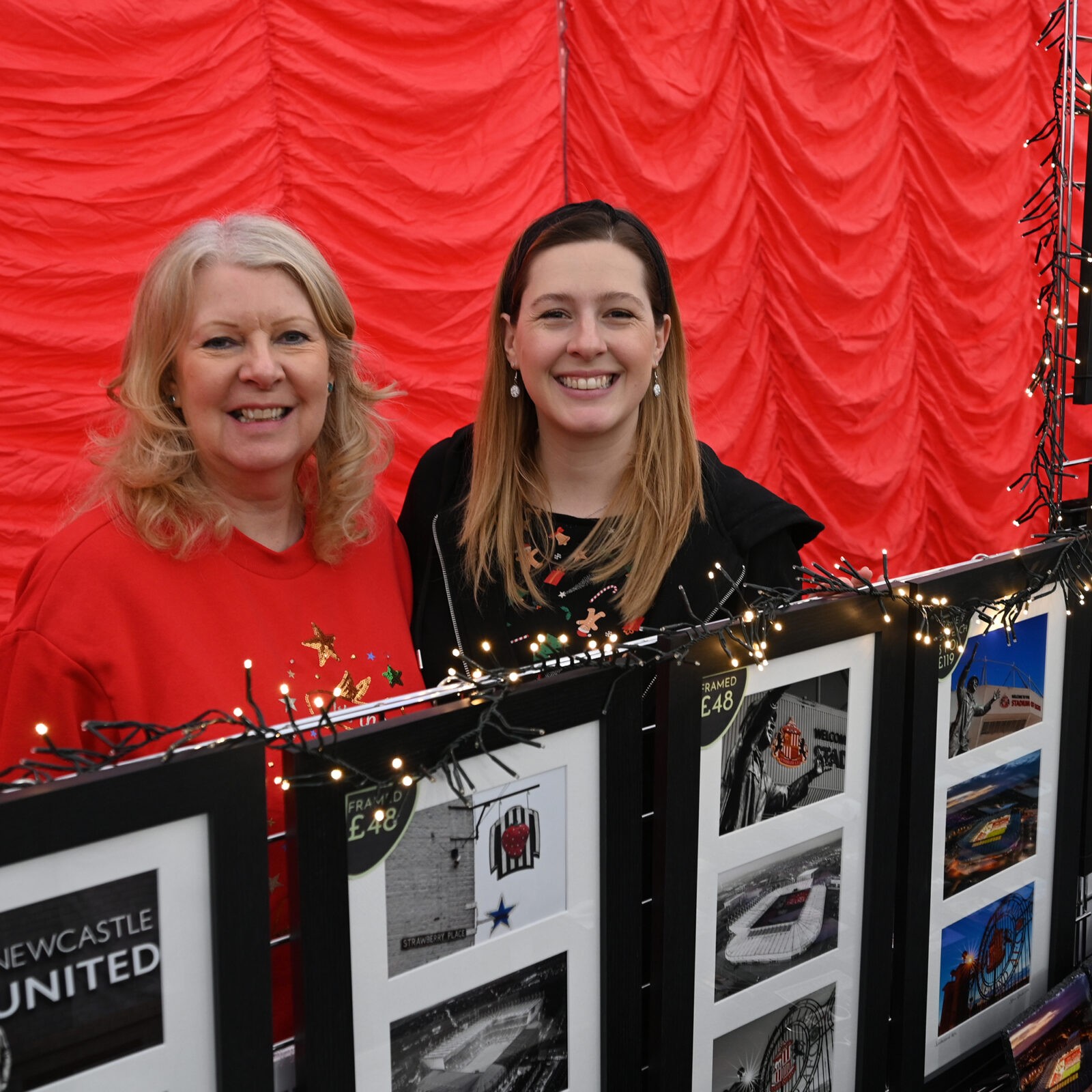 Two stallholders behind a display of photography