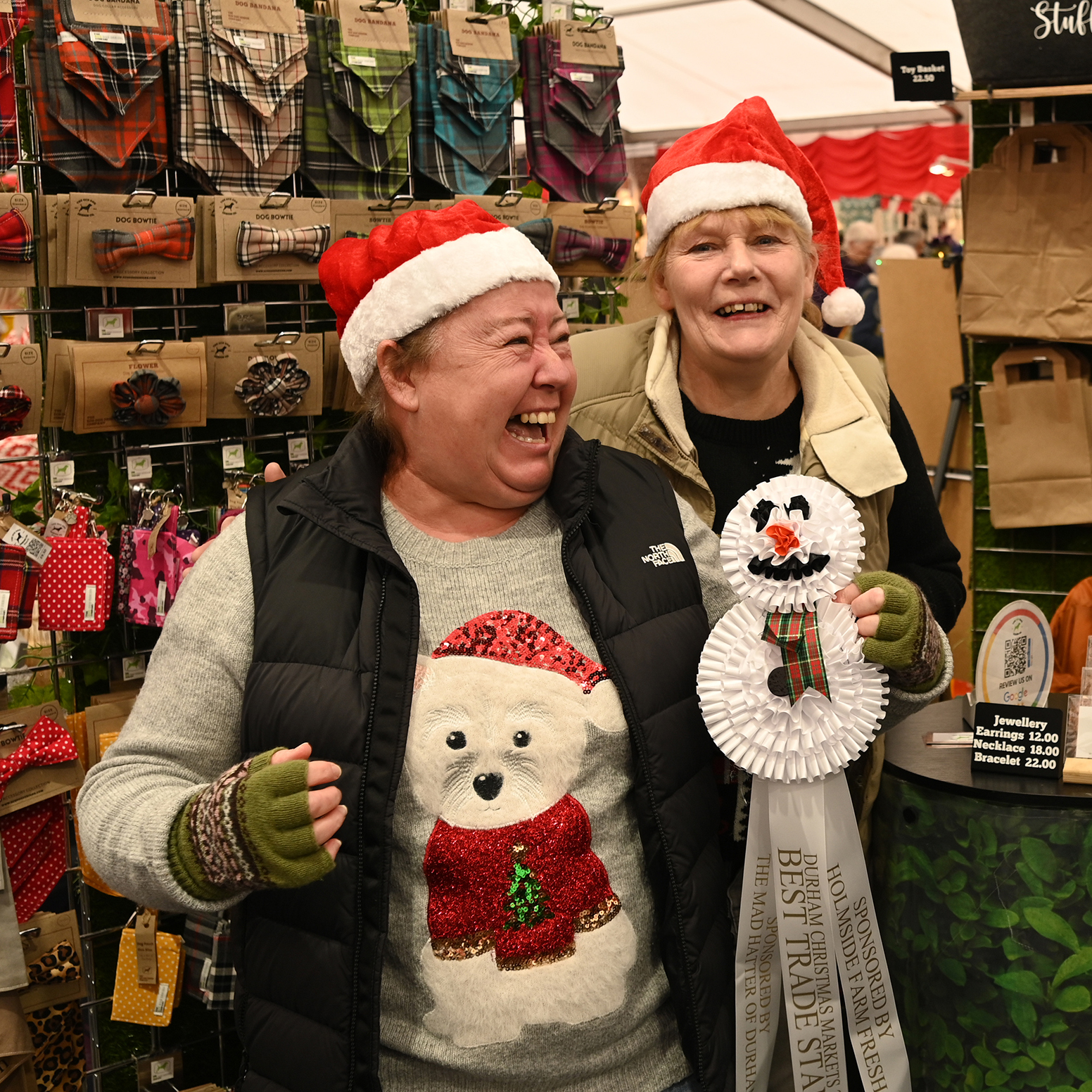 Two grinning stall holders with their best dressed stall winners rosette