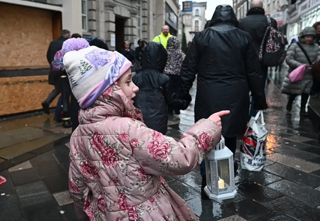 A young girl points while carrying a lantern